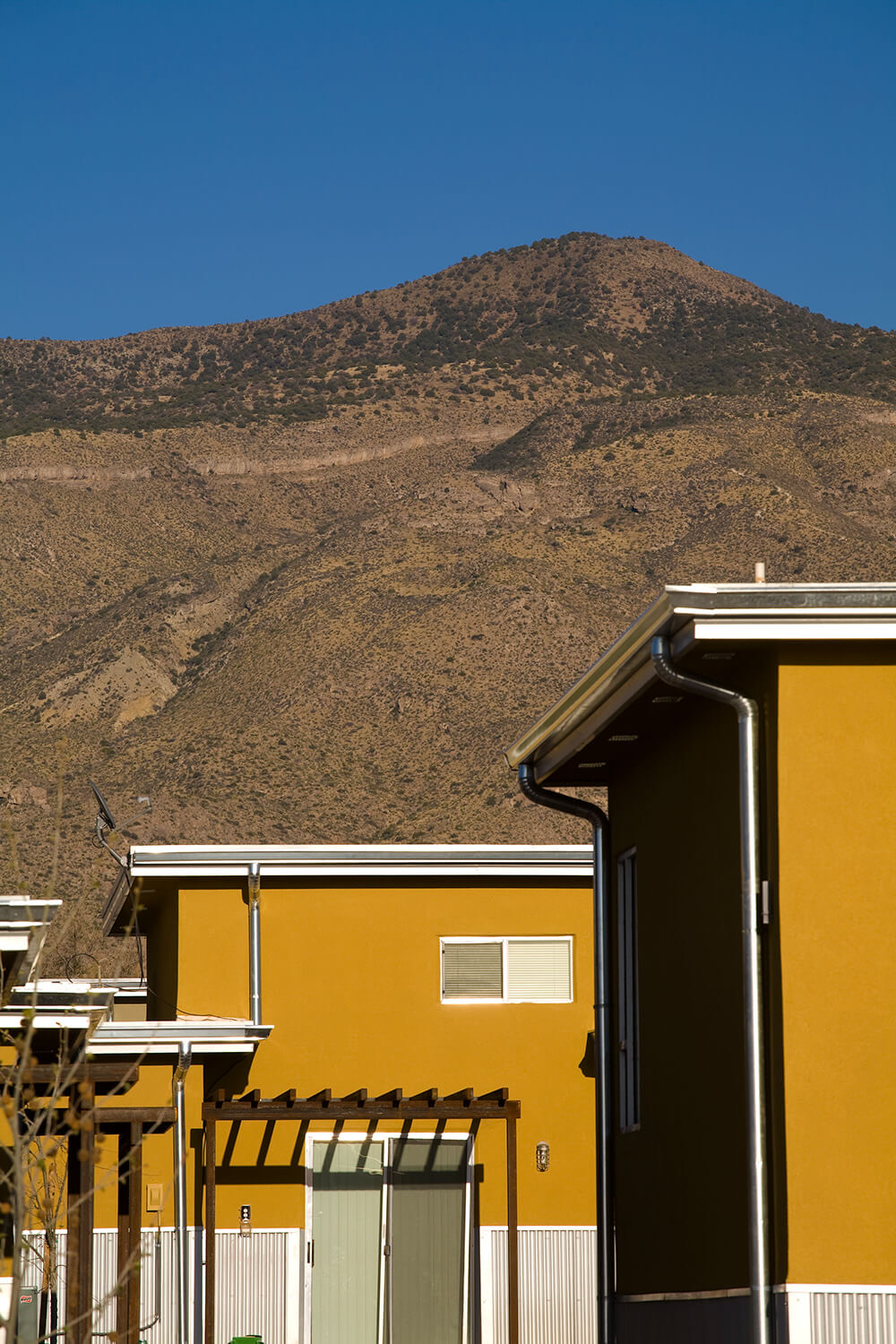 Stucco apartment homes at Cottonwood Commons with a desert mountain rising behind, Alamogordo NM