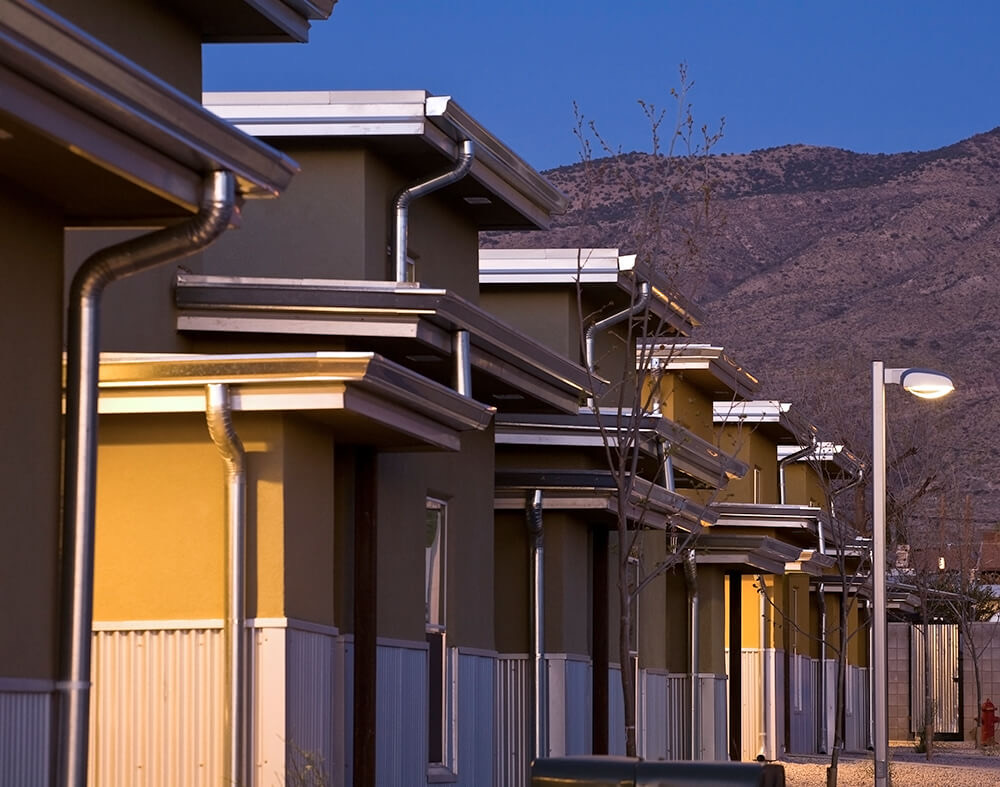 Staggered rooflines and entry canopies at Cottonwood Commons at dusk with mountains beyond